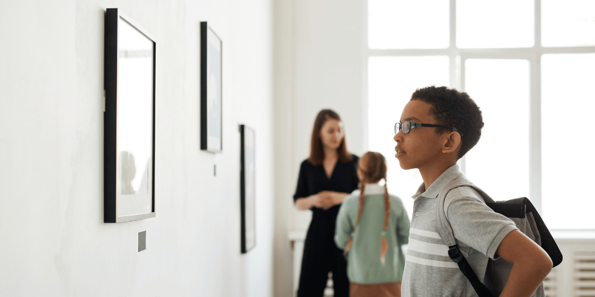 Jovem negro observando um quadro em uma exposição.